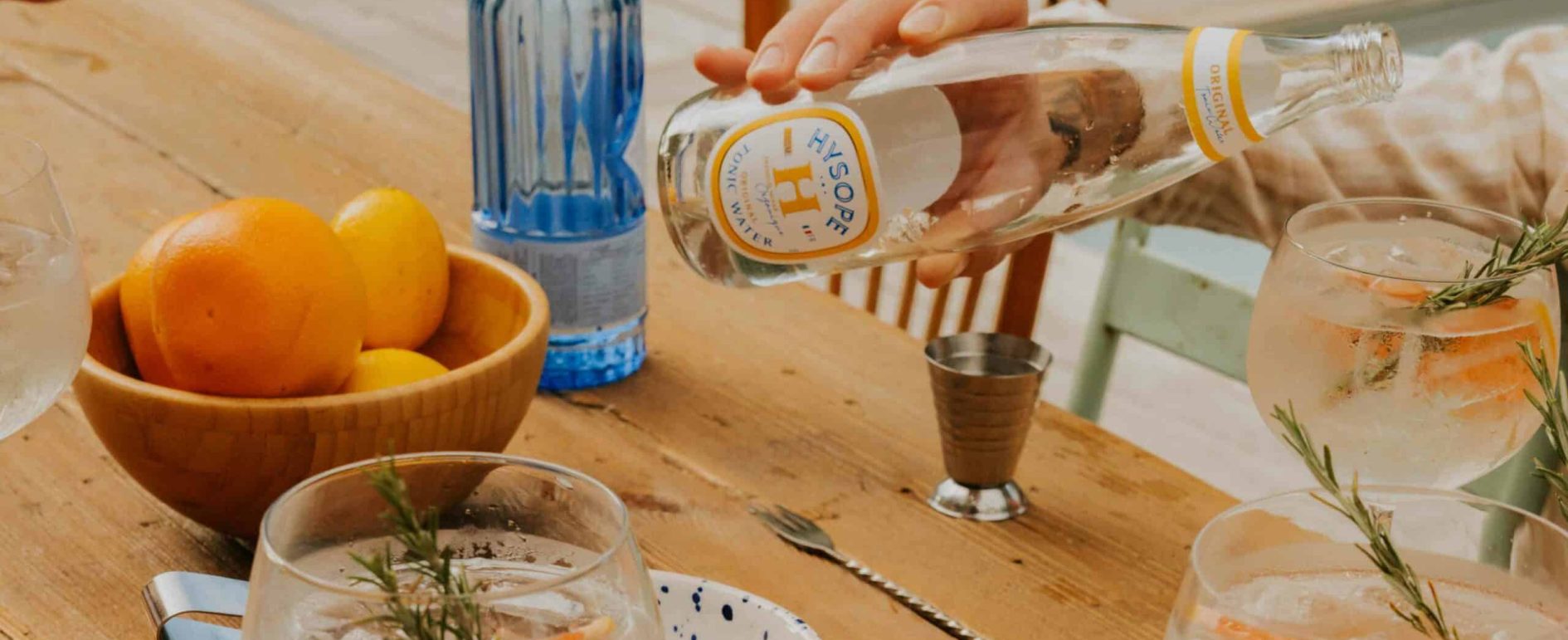 table d'été avec des verres de cocktails, des fruits et une bouteille de tonic